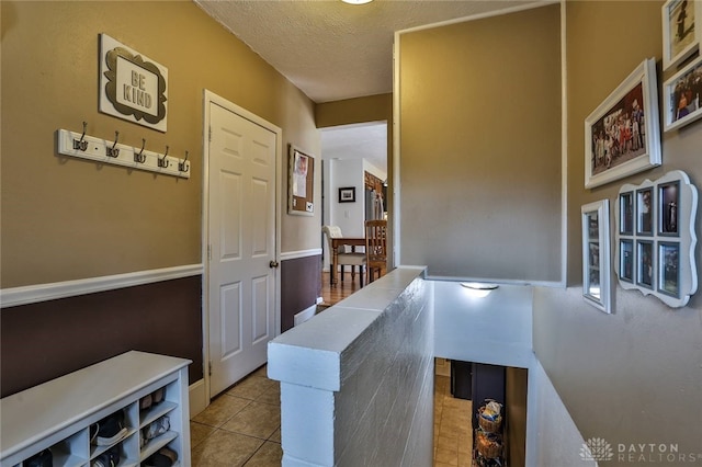 hall with tile patterned floors and a textured ceiling