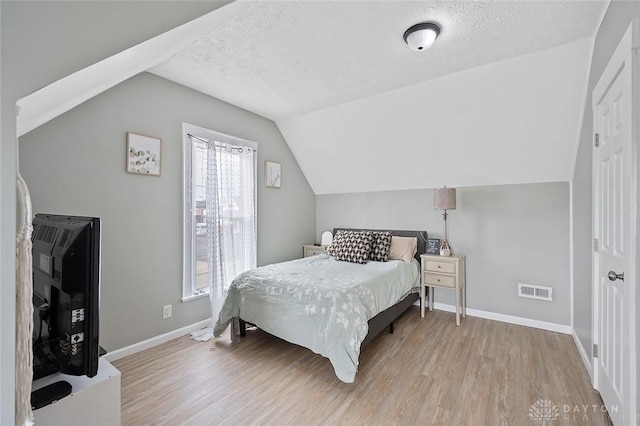 131 S Mulberry St, Troy, OH 45373 - bedroom featuring wood finished floors, vaulted ceiling, and a textured ceiling