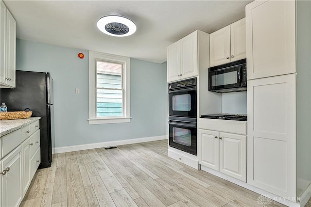 kitchen with white cabinetry, baseboards, black appliances, and light wood-style floors
