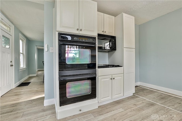 kitchen with baseboards, a textured ceiling, white cabinetry, light wood finished floors, and black appliances