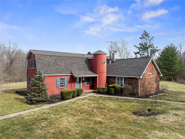 dutch colonial with a front yard, a chimney, a gambrel roof, and a shingled roof