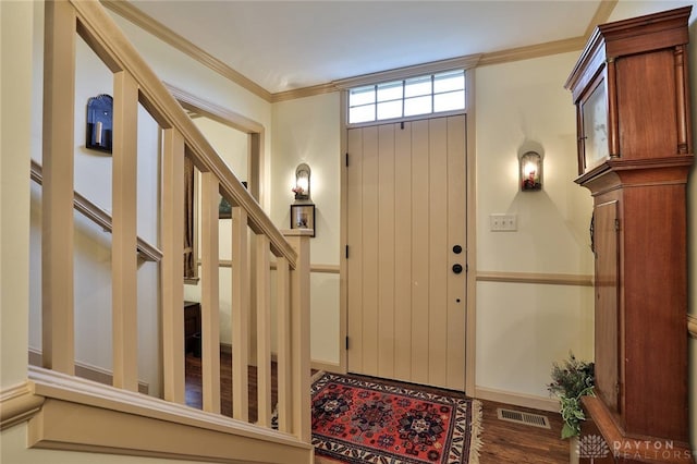foyer entrance featuring visible vents, baseboards, ornamental molding, wood finished floors, and stairs