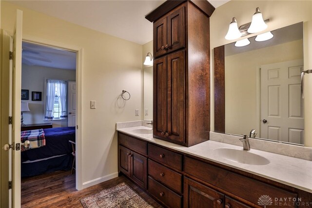 ensuite bathroom with double vanity, a sink, wood finished floors, and ensuite bath