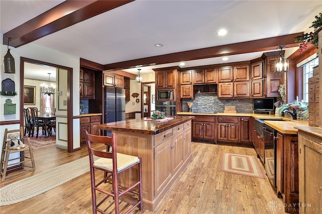 kitchen featuring light wood-style flooring, decorative backsplash, stainless steel appliances, wooden counters, and a notable chandelier