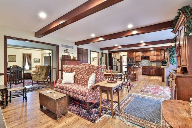 living area featuring visible vents, beamed ceiling, light wood-type flooring, and recessed lighting