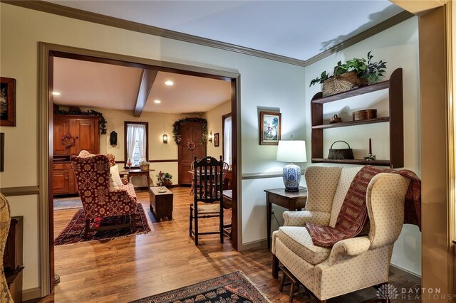 sitting room with recessed lighting, wood finished floors, beamed ceiling, ornamental molding, and baseboards