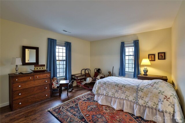 bedroom featuring dark wood finished floors, visible vents, multiple windows, and baseboards