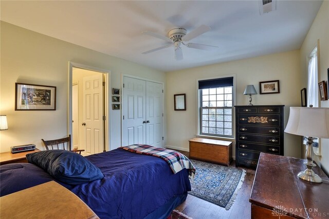 bedroom with wood finished floors, a closet, ceiling fan, baseboards, and visible vents