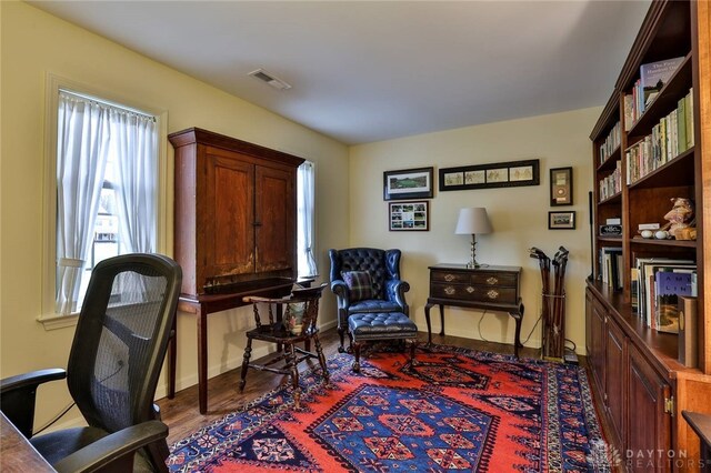 living area featuring wood finished floors, visible vents, and baseboards