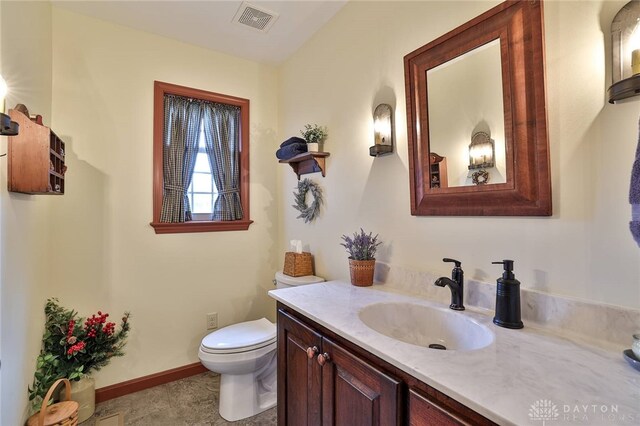 bathroom featuring visible vents, toilet, vanity, and baseboards