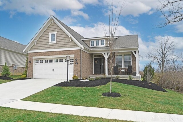 craftsman inspired home with a porch, brick siding, driveway, and a front lawn
