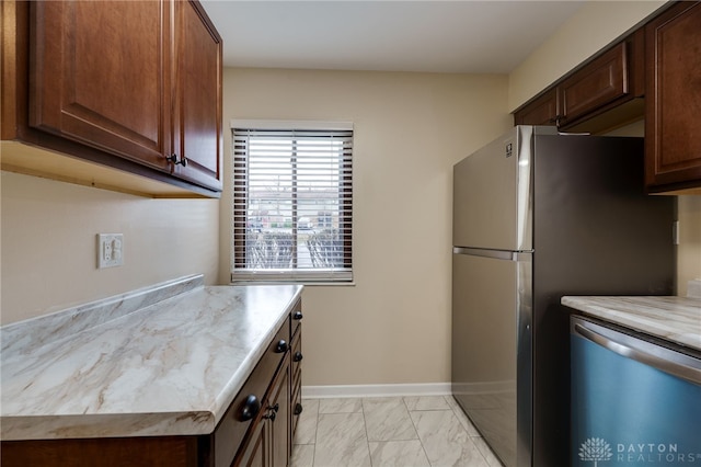 kitchen featuring baseboards, appliances with stainless steel finishes, and marble finish floor