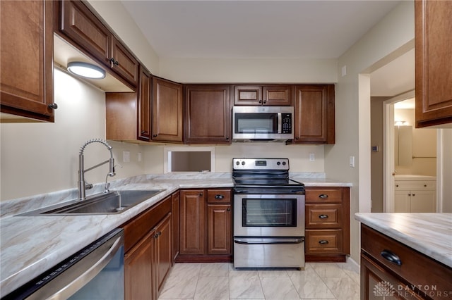 kitchen featuring stainless steel appliances, marble finish floor, light countertops, and a sink