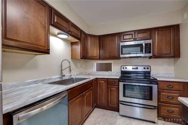 kitchen with marble finish floor, appliances with stainless steel finishes, light countertops, and a sink