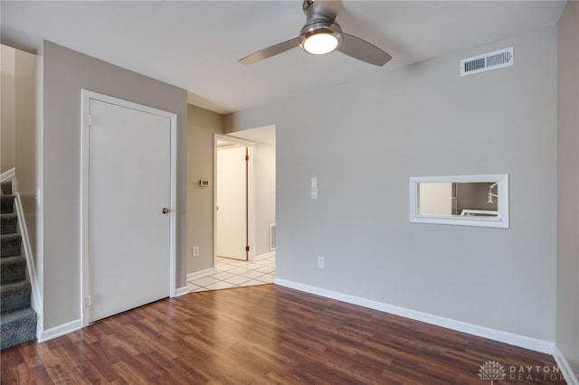 interior space featuring wood finished floors, stairs, ceiling fan, baseboards, and visible vents