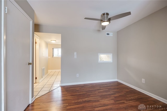 spare room with baseboards, visible vents, wood finished floors, and a ceiling fan