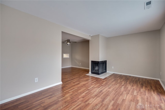 unfurnished living room with baseboards, wood finished floors, and a ceiling fan