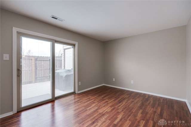 spare room featuring baseboards, visible vents, and dark wood-type flooring