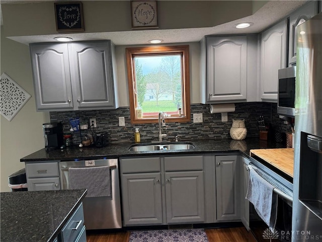 kitchen with decorative backsplash, dark stone countertops, appliances with stainless steel finishes, and a sink