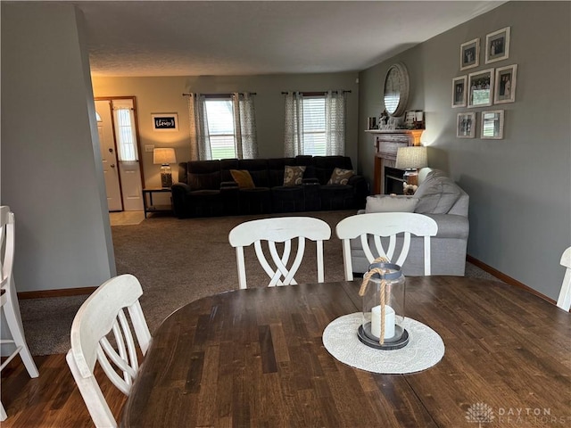 dining area featuring a fireplace, baseboards, and wood finished floors