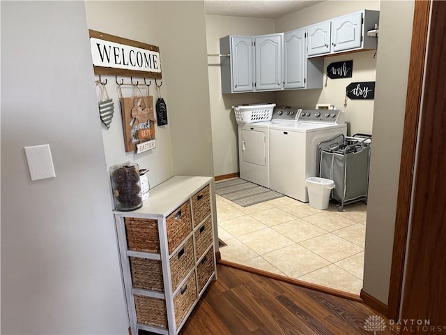 washroom featuring washer and clothes dryer, cabinet space, light wood finished floors, and baseboards