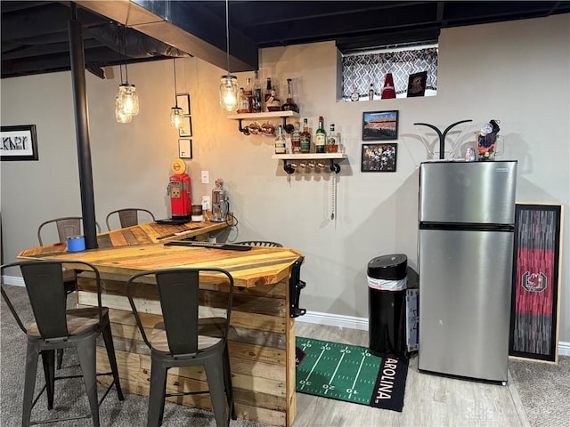 interior space with wet bar, baseboards, and wood finished floors