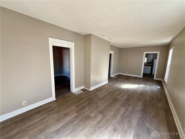 spare room featuring visible vents, baseboards, and dark wood-style flooring