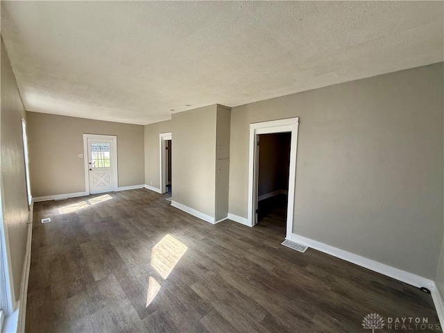 unfurnished room with dark wood finished floors, baseboards, and a textured ceiling