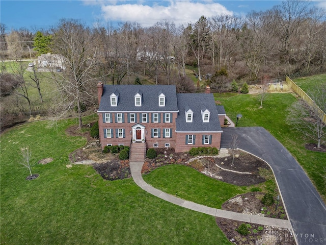 view of front of property with a chimney, brick siding, and a front yard
