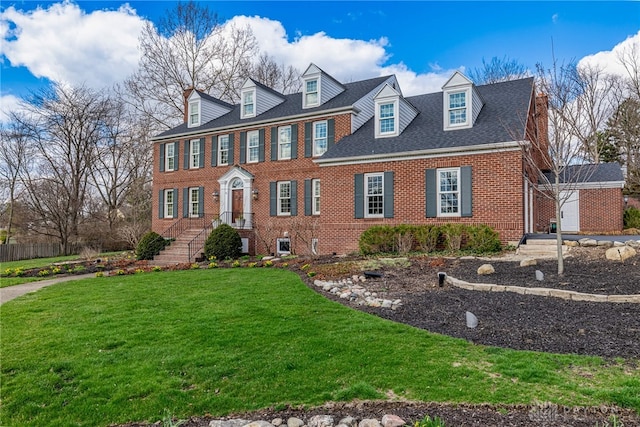 colonial house featuring a front lawn, fence, and brick siding