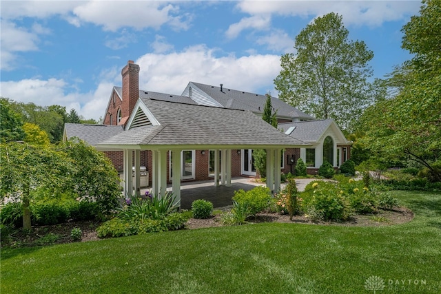 533 Lockerbie Ln, Kettering, OH 45429 - view of front facade featuring a shingled roof, a front lawn, a patio area, and a chimney