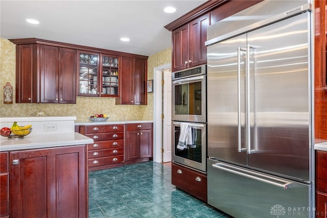 533 Lockerbie Ln, Kettering, OH 45429 - kitchen featuring stainless steel appliances, wallpapered walls, dark brown cabinets, light countertops, and glass insert cabinets