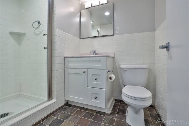 bathroom featuring toilet, stone finish floor, vanity, and a stall shower