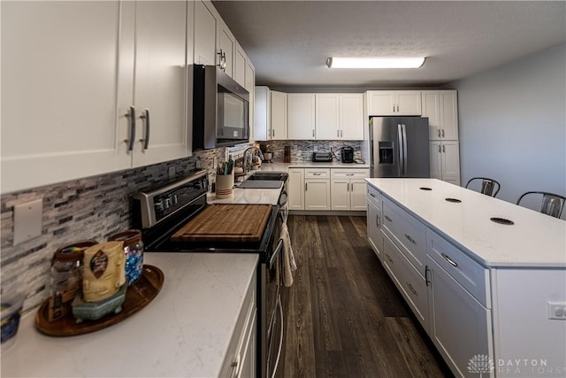 kitchen with decorative backsplash, electric range oven, a sink, white cabinetry, and stainless steel refrigerator with ice dispenser
