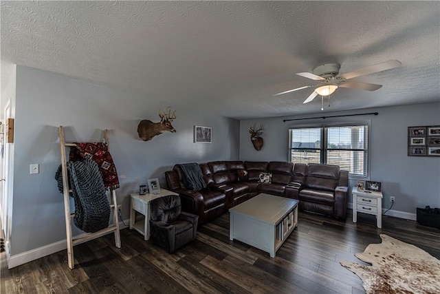 living room featuring a ceiling fan, a textured ceiling, and dark wood-type flooring
