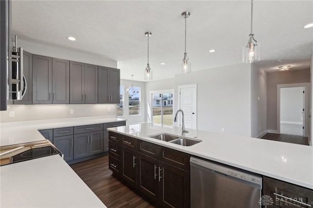 kitchen featuring light countertops, a sink, stainless steel dishwasher, and dark wood finished floors