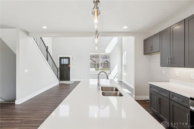 kitchen with light countertops, recessed lighting, hanging light fixtures, a sink, and dark wood-style floors