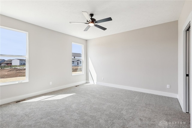 unfurnished room featuring visible vents, carpet, baseboards, and ceiling fan