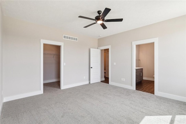 unfurnished bedroom featuring baseboards, dark colored carpet, and visible vents