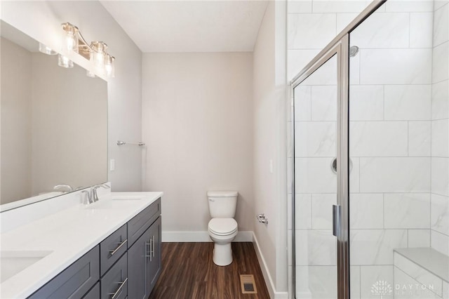bathroom with toilet, baseboards, a shower stall, a sink, and wood finished floors