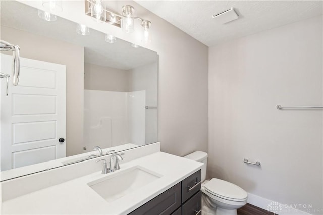 bathroom with baseboards, vanity, toilet, and walk in shower