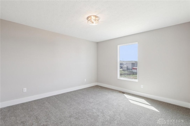 carpeted empty room featuring baseboards and a textured ceiling