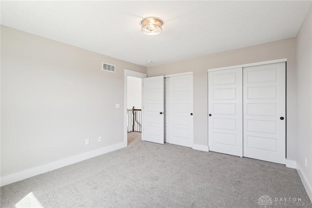 unfurnished bedroom with two closets, carpet, baseboards, and visible vents