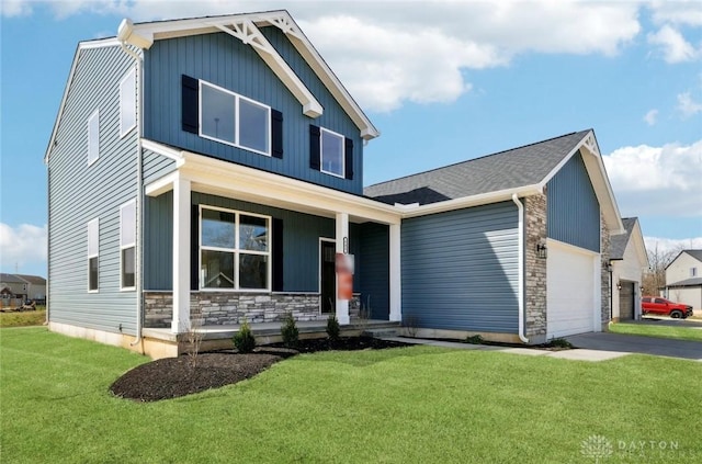 view of front of home with stone siding, a front yard, a garage, and covered porch