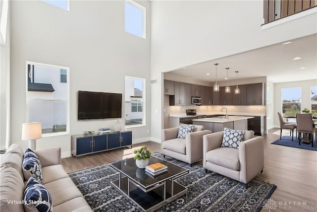 living room featuring baseboards, light wood-type flooring, and a high ceiling