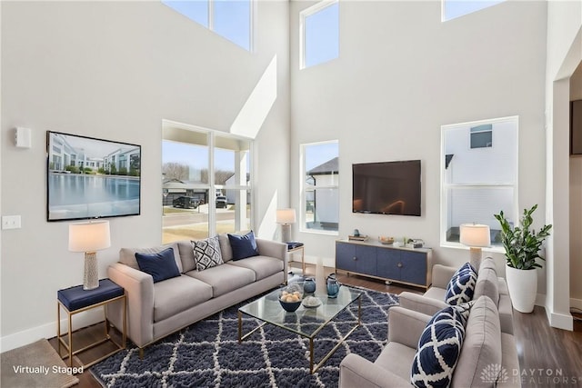 living room featuring baseboards, a high ceiling, and wood finished floors