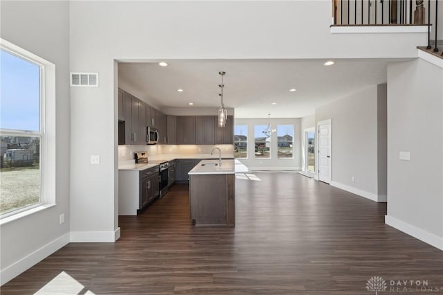 kitchen with light countertops, a sink, appliances with stainless steel finishes, open floor plan, and visible vents