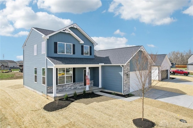view of front facade with stone siding, an attached garage, driveway, covered porch, and a shingled roof
