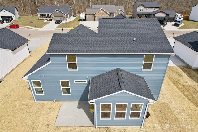 rear view of house featuring a residential view and a shingled roof