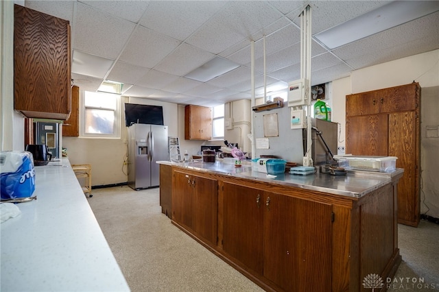 531 W Ash St, Piqua, OH 45356 - kitchen featuring stainless steel counters, stainless steel fridge with ice dispenser, plenty of natural light, brown cabinetry, and a paneled ceiling